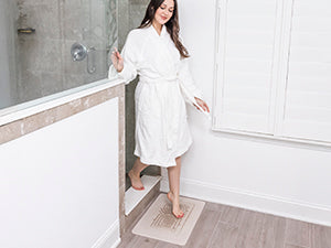 Woman's feet stepping onto a quick-drying diatomaceous earth bath mat.